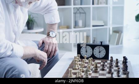 partial view of elderly man playing chess in living room,stock image Stock Photo