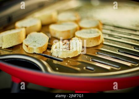 Prepare breakfast with bread, roasting bruschetta on the barbecue gas grill outdoor in the backyard, Breakfast on grill, summer family picnic, food on Stock Photo