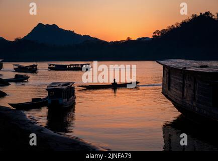 Local ferry boats in the Mekong River at sunset, Luang Prabang, Laos Stock Photo