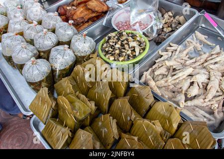 The offer of Thai market, Isan-style mushroom soup in a plastic bags, Steamed Fish in Red Curry Mousse wrapped in leaf and other. Stock Photo