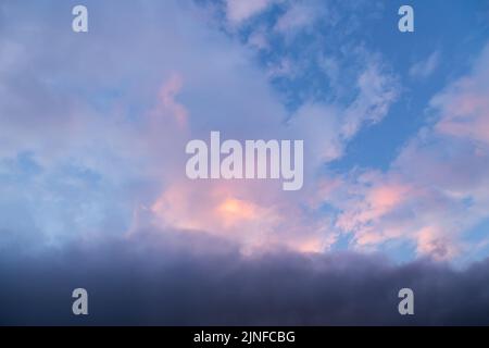 Dramatic clouds at sunset illuminated by the sun in orange Stock Photo