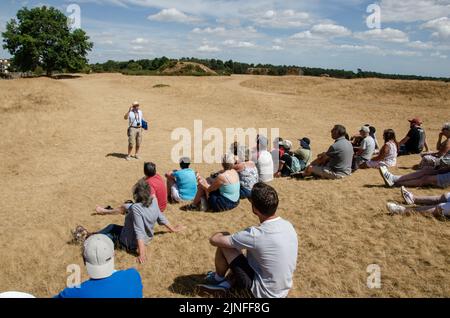 Guide speaking to tourists at the site of the Anglo-Saxon burial gounds at Sutton Hoo, Suffolk, England, UK Stock Photo