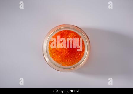 side view of closed glass jar with red caviar of pink salmon isolated on white background. Stock Photo