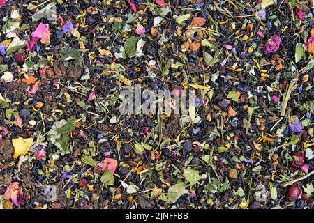 Texture of dry black tea mixed with herbs, leaves and dried berries. Mixed herbal vitamin tea background. Stock Photo