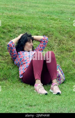 Middle aged woman lying on grassy bank Stock Photo
