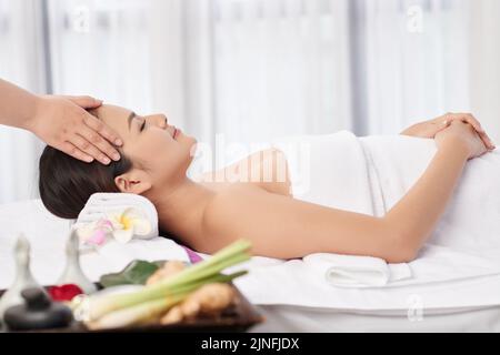 Smiling pretty young woman getting relaxing head massage Stock Photo