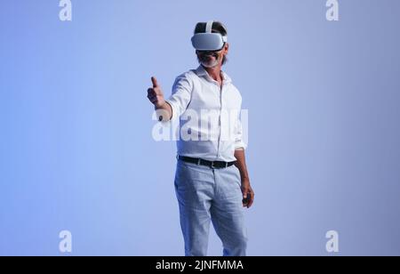 Closing business deals in the metaverse. Senior businessman giving a virtual handshake to a business partner. Successful businessman wearing a virtual Stock Photo