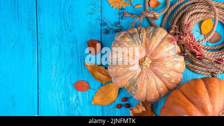 A composition with pumpkins and autumn foliage on a blue wooden background. Stock Photo