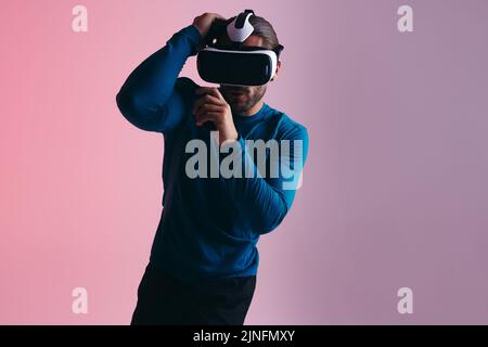 Boxing in virtual reality. sporty young man preparing for a virtual punch while wearing virtual reality goggles. Active young man exploring virtual re Stock Photo