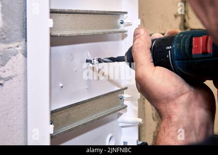 Power drill at electrical work is used to drilling hole in distribution board. Stock Photo