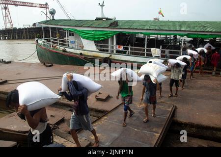 Yangon. 11th Aug, 2022. Workers unload bags of rice from a cargo boat at a jetty in Yangon, Myanmar on Aug. 11, 2022. Myanmar's agricultural export earnings decreased 1.25 percent to about 1.27 billion U.S. dollars year on year in the first four months of the present fiscal year (FY) 2022-2023, according to the Ministry of Commerce. The Southeast Asian country changed its fiscal year from the original October-September to April-March beginning this year. Credit: Myo Kyaw Soe/Xinhua/Alamy Live News Stock Photo