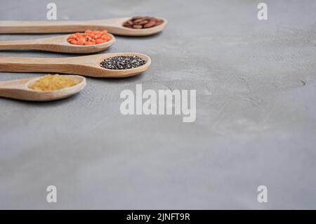 Different or various types of dry beans or dried legumes in wooden spoon on gray background. Whole grains, healthy food and diet concept Stock Photo