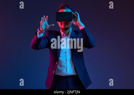 Smiling businessman using virtual reality headset in darkness Stock Photo