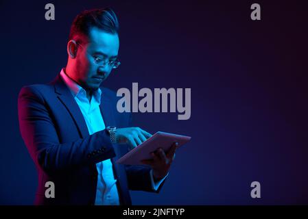 Confident Vietnamese entrepreneur using application in digital tablet Stock Photo