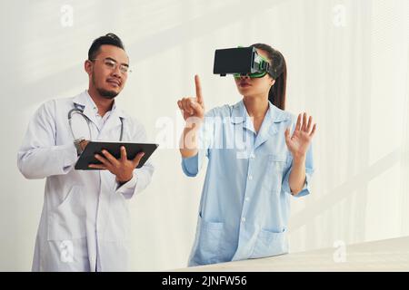 Doctors using application on tablet computer to test VR goggles Stock Photo