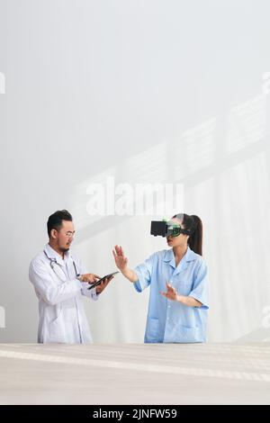 Doctor and nurse with headset and digital tablet testing VR simulator application Stock Photo