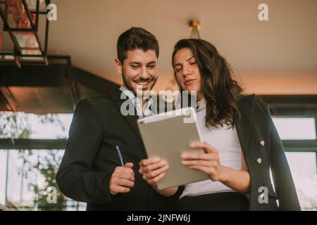 Two business partners talking while looking at the tablet at the cafe Stock Photo