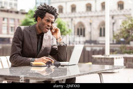 Working Outdoors. A young London business professional enjoying working out of the office. From a series of related images with the same model. Stock Photo