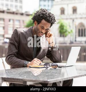 Working Outdoors. A young London business professional enjoying working out of the office. From a series of related images with the same model. Stock Photo