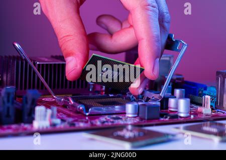 A man's hand inserts a processor into the motherboard socket. Stock Photo