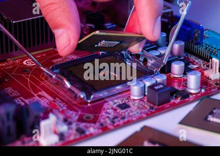 A man's hand inserts a processor into the motherboard chipset. Stock Photo