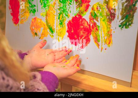 little girl artist with paints in her hands in autumn in the park draws a landscape with leaves on canvas Stock Photo