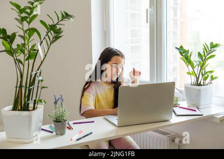 Little girl learning English indoors at online lesson Stock Photo