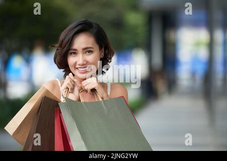 Portrait of attractive young Asian woman holding shopping bags Stock Photo