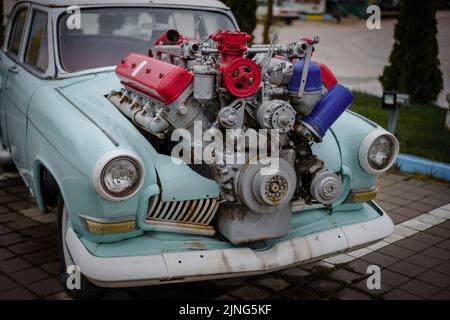 Image of a vintage tuned car, with a large engine sticking out of its hood. Stock Photo