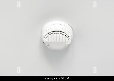Smoke detector or fire alarm sensor on white ceiling. Stock Photo
