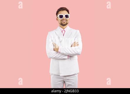Portrait of funny cool and stylish young man in suit isolated on pastel pink background. Stock Photo