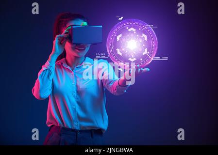 Business lady in virtual reality headset looking at innovative interface in her hand Stock Photo