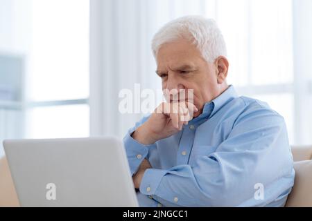 Portrait of pensive aged man learning how to work on laptop Stock Photo