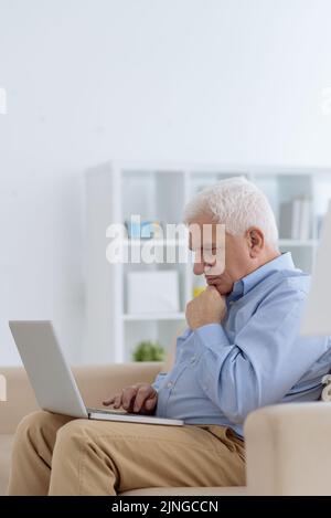 Concentrated aged man reading information on laptop screen Stock Photo