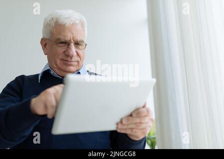 Senior man in glasses learning how to use tablet computer Stock Photo