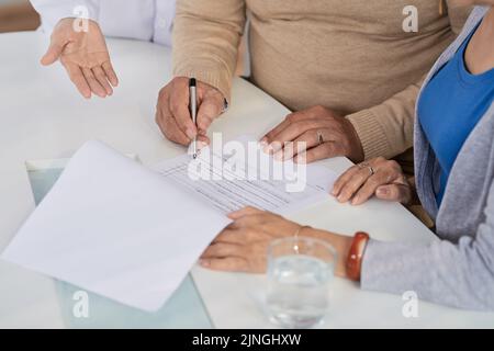 Close-up shot of loving senior couple filling in form while visiting highly professional physician together Stock Photo