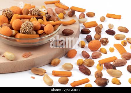 Mixed roasted nuts and peanuts peeled in a glass bowl, against a wooden board. Close up view. Stock Photo