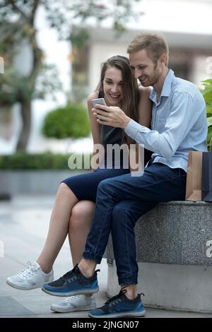 Cheerful couple using smartphone application together after shopping Stock Photo