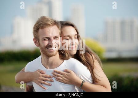 Happy young man being embraced by his loving beautiful wife Stock Photo