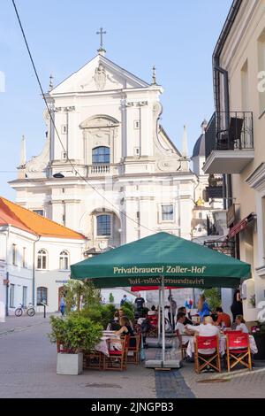 Vilnius Old Town street scene with the Church of St Theresa and people at a cafe; Vilnius, Lithuania Travel, Lithuania Europe Stock Photo