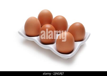 Half a dozen or 6 eggs in white ceramic tray holder isolated on white Stock Photo