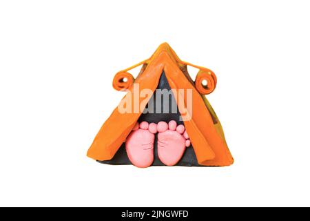The heels stick out of the orange tent. Made from plasticine. Isolated on white. Stock Photo