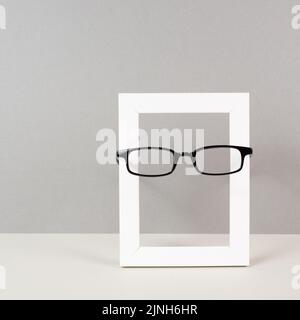 Home interior poster mock up with wooden frame and eyeglasses, gray wall background, copy space for text and pictures Stock Photo