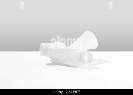 Monochrome composition of plastic bottles lying on a white surface. Negative impact on nature. The concept of environmental damage. Stock Photo
