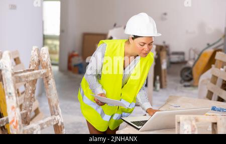 Focused female civil engineer using laptop at construction site Stock Photo