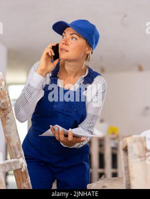 Young woman engineer in uniform is talking on a mobile phone Stock Photo