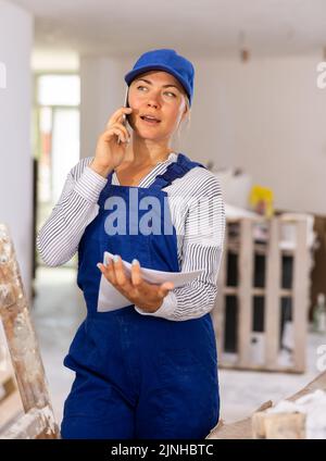 Woman builder having telephone conversation in construction site Stock Photo