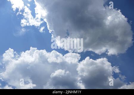 fluffy white cumulus clouds tinged with dark gray Stock Photo