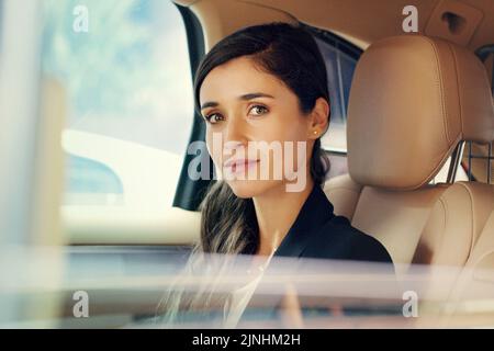 Always be content in taking the backseat when you succeed. Portrait of an attractive young businesswoman sitting inside a car while travelling to work Stock Photo