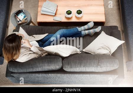 Being content with yourself removes unwanted company. an attractive young woman sitting on sofa while relaxing at home drinking coffee. Stock Photo